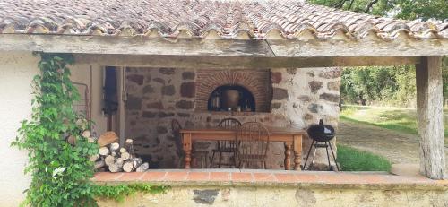 a porch of a stone house with a table and chairs at Les Ecots - Petit gîte de caractère à la ferme in Availles-Limouzine