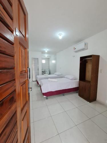 1 dormitorio con 2 camas y puerta de madera en Pousada Jereissati, en Maracanaú