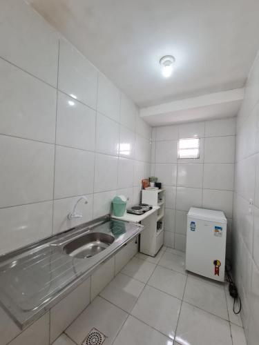 a small white kitchen with a sink and a refrigerator at Pousada Jereissati in Maracanaú