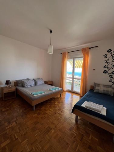 a bedroom with two beds and a large window at Apartments Andrović in Ulcinj