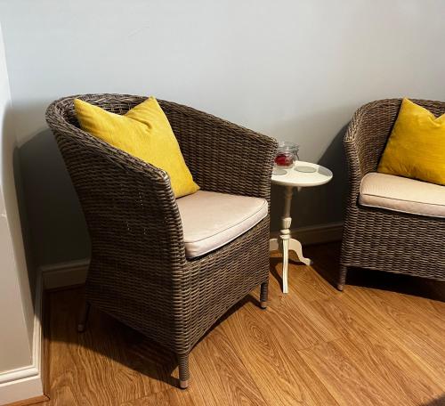 two wicker chairs with yellow pillows and a table at Flavian House in Chichester