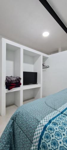 a white bedroom with a bed and a tv at Loft A in Hidalgo del Parral