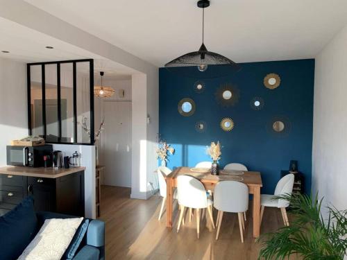 une salle à manger avec une table et un mur bleu dans l'établissement Appartement Rouen terrasse + parking, à Rouen