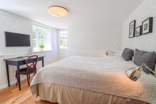 a bedroom with a bed and a desk and a television at Stammershalle Badehotel in Bådsted