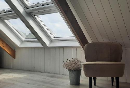 a chair sitting in a room with a skylight at Rustiek Andijk in Andijk