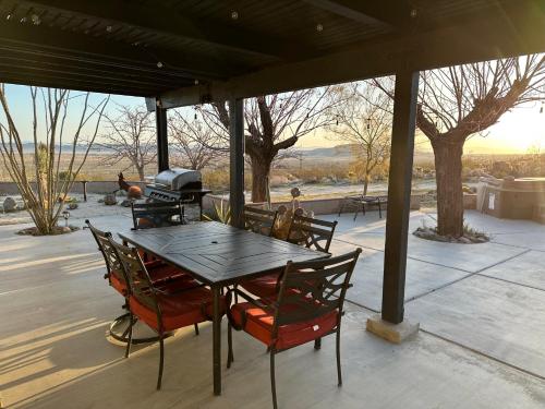 a table and chairs on a patio with a grill at The Outpost Joshua Tree: Hot Tub, GameRoom, JTNP in Joshua Tree