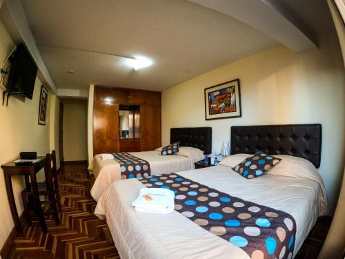 a hotel room with three beds and a television at Hotel Casa Santa Beatriz in Cusco