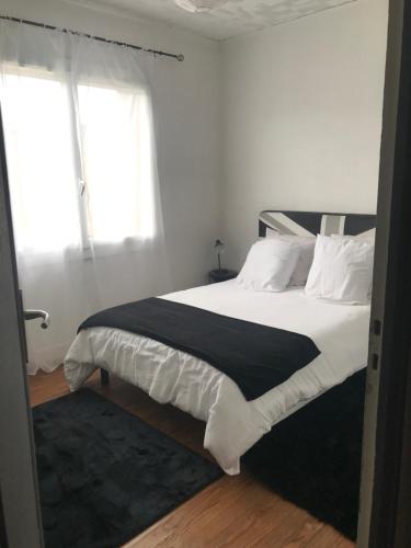 a bedroom with a bed with white sheets and a window at Appartement spacieux et lumineux in Mugron