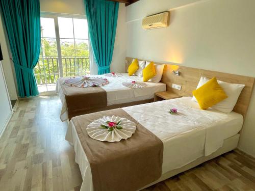 two beds in a hotel room with blue curtains at Güneş Boutique Hotel - Oludeniz in Oludeniz