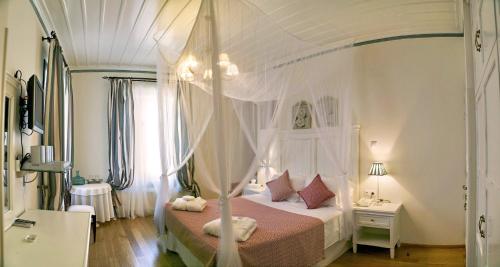 ein Schlafzimmer mit einem weißen Himmelbett mit rosa Bettwäsche in der Unterkunft Archontiko Petras 1821 in Petra