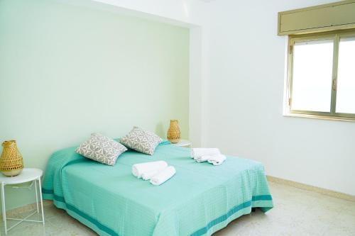um quarto branco com uma cama com toalhas em Casa sul mare vicino Marina di Ragusa em Villaggio Azzurro
