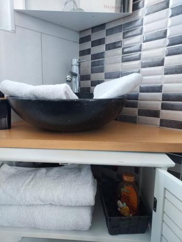 - une salle de bains avec un bol noir sur un comptoir et des serviettes dans l'établissement Appartement meublé avec deux chambres, à Moulins