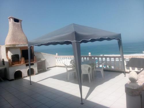 une terrasse avec une table et un parasol et l'océan dans l'établissement Villa Keltoum, à Moulay Bousselham