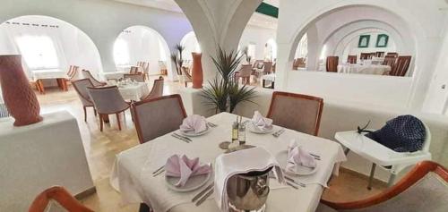 a dining room with white tables and chairs and a restaurant at Zenon Djerba in Midoun