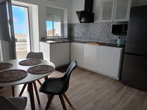 a kitchen with a table and chairs and a kitchen with white cabinets at La Lunita in Valverde