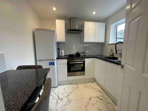 a kitchen with a white refrigerator and a table at Modern 1 Bedroom Studio Flat in Northfleet