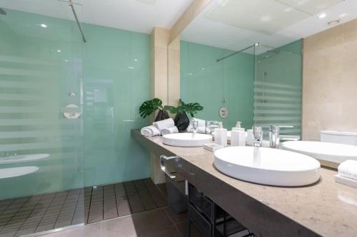 W łazience znajdują się 2 umywalki i przeszklony prysznic. w obiekcie Impresionante apartamento en edificio de lujo SELTON PLAZA ESPAÑA w Madrycie