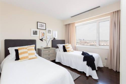 biała sypialnia z 2 łóżkami i oknem w obiekcie Impresionante apartamento en edificio de lujo SELTON PLAZA ESPAÑA w Madrycie