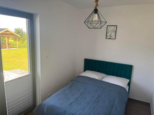 um quarto com uma cama com um edredão azul e uma janela em Apartamenty Pod Jodłami em Sarbinowo