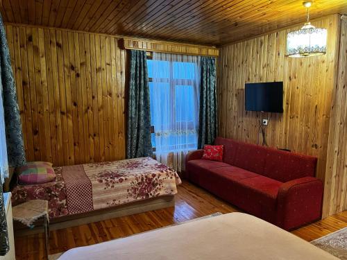 Habitación con sofá rojo, cama y ventana en Zirve Apart, en Uzungöl