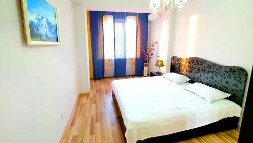 a bedroom with a white bed and a window at Stylish apartment in the city center in Bishkek