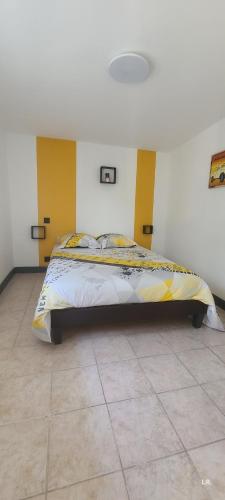 um quarto com uma cama com uma cabeceira amarela em Gîte - LE RAZAL em Vallon-Pont-dʼArc