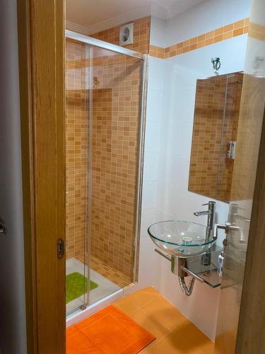 ein Badezimmer mit einem Glaswaschbecken und einer Dusche in der Unterkunft Apartamento Duplex O capitán in A Guarda