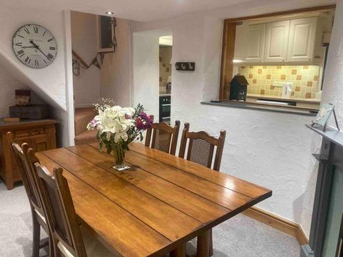 a dining room table with a vase of flowers on it at Main Street 2 bedroom town house in Llandeilo