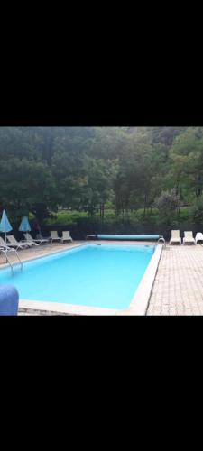 une grande piscine bleue avec chaises et parasols dans l'établissement Mobil home, à Villefranche-de-Conflent