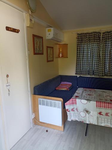 Cette petite chambre dispose d'un canapé bleu et d'un lit. dans l'établissement Mobil home, à Villefranche-de-Conflent