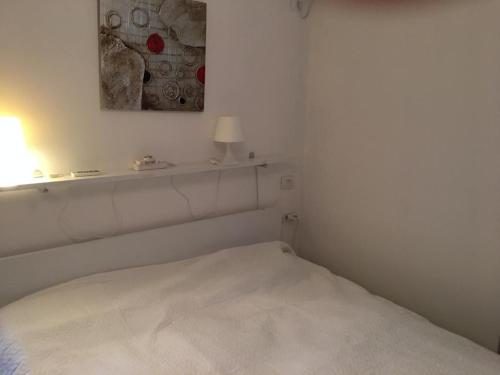 a white bed in a white room with a lamp at Apartman Martini in Orikum