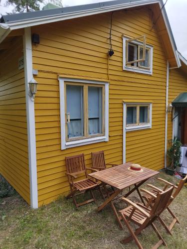 a table and chairs outside of a yellow house at Mysig Stuga På Houtskär in Houtskari