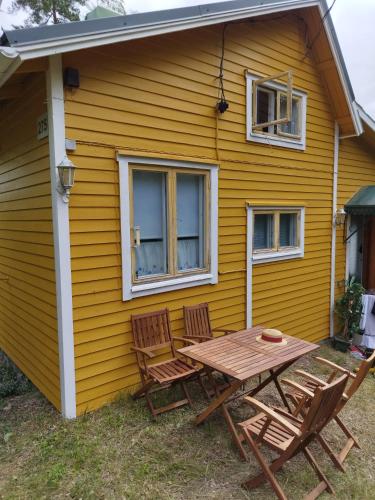 une table et des chaises à l'extérieur d'une maison jaune dans l'établissement Mysig Stuga På Houtskär, à Houtskari