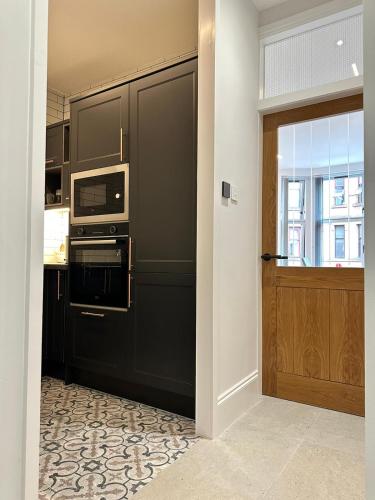 cocina con nevera negra y microondas en Glasgow West End Tenement Apartment, en Glasgow