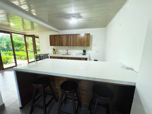 a kitchen with a counter with three bar stools at La Casa Pina Pacifica near La Fortuna in San Ramón