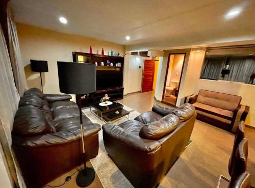 uma sala de estar com sofás de couro e uma televisão em Apartment em Cusco