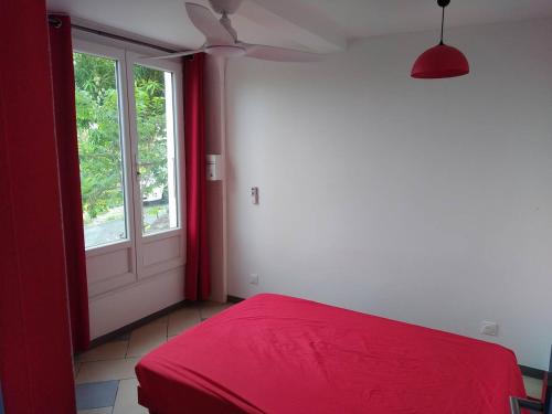 a bedroom with a red bed and a window at Stephane in Pointe-Noire
