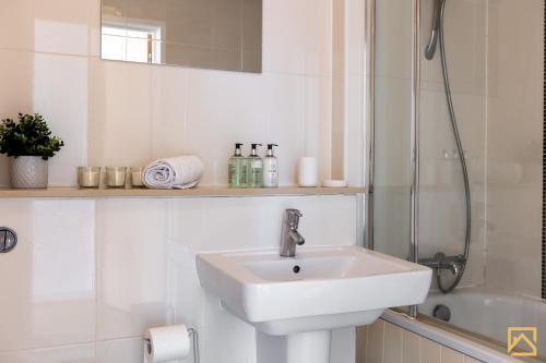 a white bathroom with a sink and a shower at Stunning 1-bed, Central MK, Free Parking, Smart TV By Valore Property Services in Milton Keynes