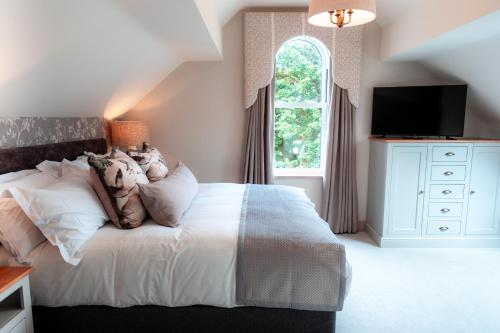 a bedroom with a white bed and a window at The Ruddings in Keswick