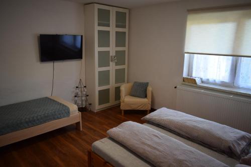 1 dormitorio con 2 camas, TV y silla en Ubytovanie u Adama en Oščadnica