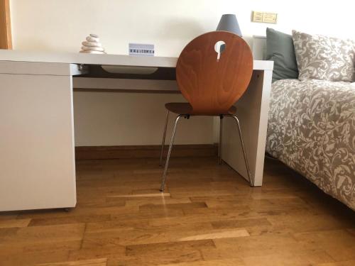 a wooden chair sitting under a desk next to a bed at Private Ensuite beachside in Parede