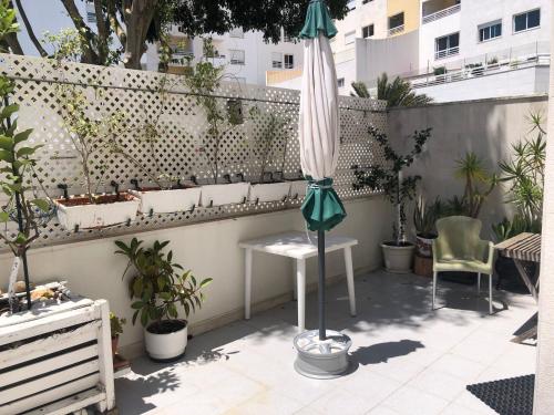 een patio met een tafel, een parasol en planten bij Private Ensuite beachside in Parede