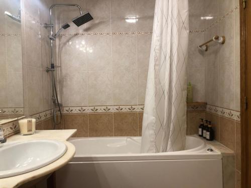 een badkamer met een bad, een wastafel en een douche bij Private Ensuite beachside in Parede