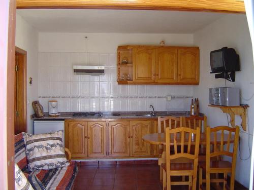 a kitchen with wooden cabinets and a table and a couch at Casa Time in Tijarafe