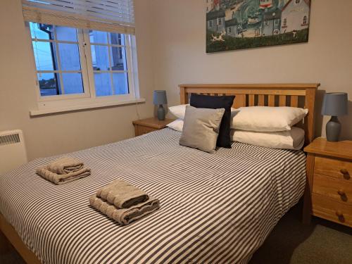 a bedroom with a bed with two towels on it at Seven Bays Stays in St Merryn