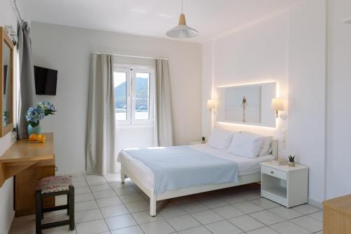 a white bedroom with a bed and a window at Ormos Atalia in Bali