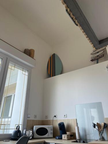 a kitchen with a counter with a microwave and a window at Ma cabane à la plage de Dunkerque, Duplex bord de mer accès direct plage en rdc, Malo les Bains in Dunkerque