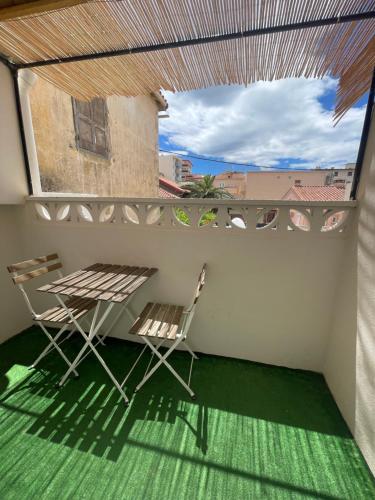 a balcony with two chairs and a table and a window at Ezz'Hotel Canet in Canet-en-Roussillon
