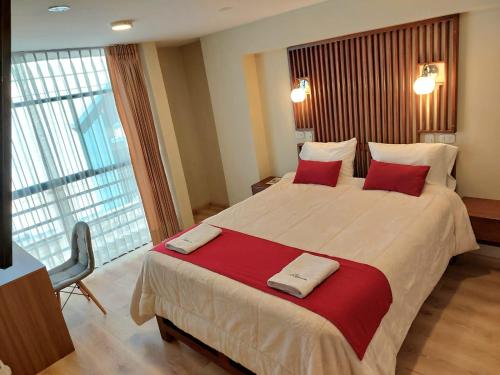 una camera d'albergo con un grande letto con cuscini rossi di Hotel California a Juliaca