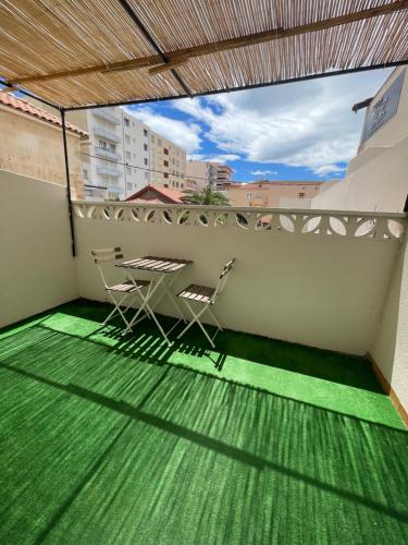 a balcony with a table and chairs on a green floor at Ezz'Hotel Canet in Canet-en-Roussillon